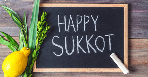 A small blackboard with the words “Happy Sukkot” written on it. Traditional Lulav and Etrog are next to the board.